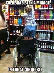 Woman in wheelchair viewed from behind, standing up to get a bottle of alcohol off a store shelf. Caption says there has been a miracle in the alcohol isle.