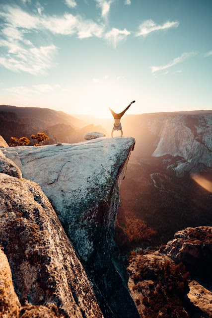Man doing handstand on cliff at sunset