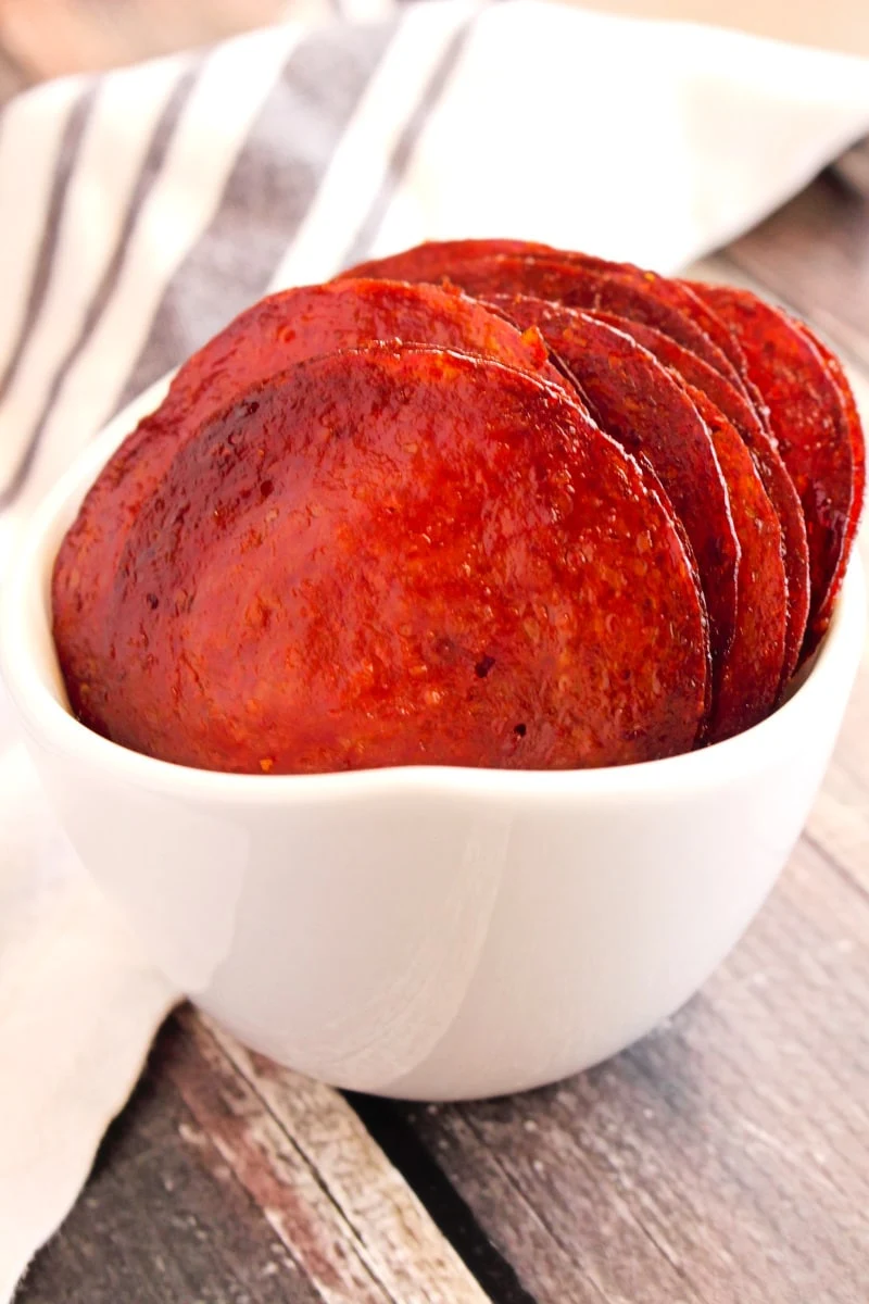 Pepperoni Chips in a white bowl on a rustic wood background.