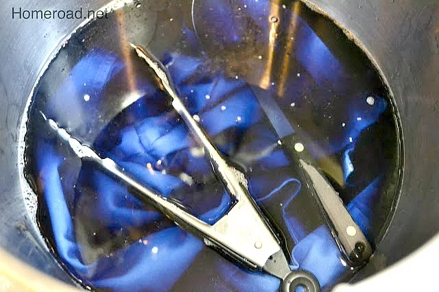 pot of t shirts in blue dye with tongs