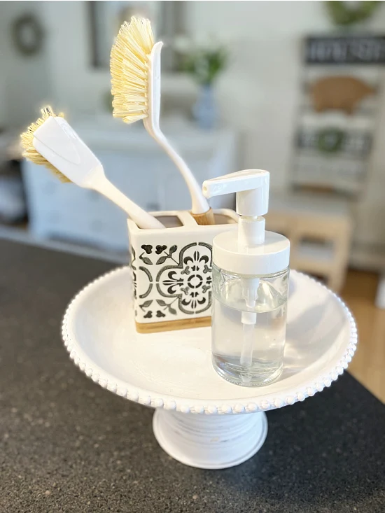 pedestal dish by the sink with brushes and soap