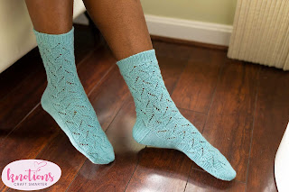 A person wearing a pair of pale blue fingering-weight lace socks