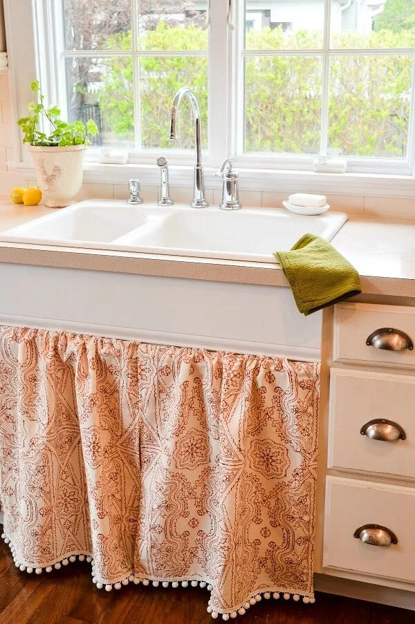 A red and white skink skirt with fringe in a cottage style off white kitchen.