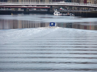 A small boat creates huge ripples on a previously still river Tyne