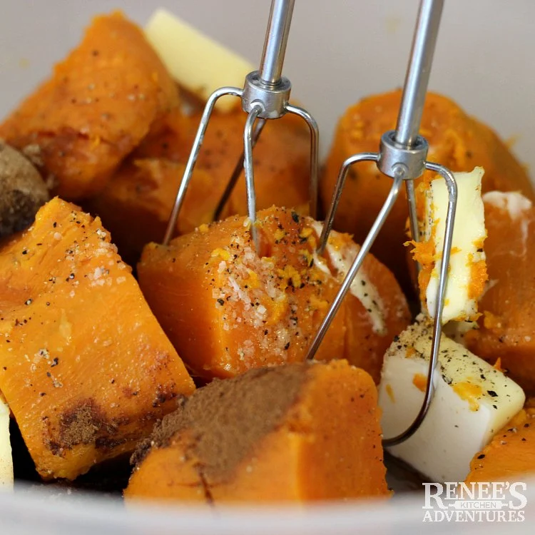 Cooked sweet potatoes in a white bowl with ingredients and two beaters from electric mixer ready to mix for Sweet Potato Souffle Casserole by Renee's Kitchen Adventures
