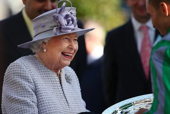 The Queen wore a pastel purple dress which featured a knee-length pleated skirt and a long quilted coat with three layers of pearls necklece