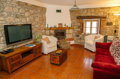 Sala de la casa, con el sofá a la deracha, tele a la izquierda y ventana y chimenea  al fondo a