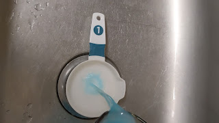 blue fluid being poured into a baking soda filled measuring cup