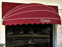 Bir dükkan üzerinde takılı olan kırmızı körüklü tente
