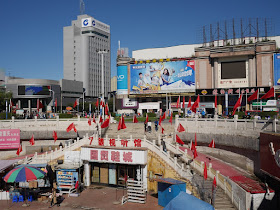 Chinese and red flags surrounding the Guomao Shopping Center (国贸商城) at Culture Square (文化广场) in Mudanjiang, China
