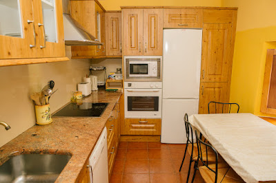 cocina con encimera a la izquerda, mesa a la derecha y nevara, horno y microondas al fondo