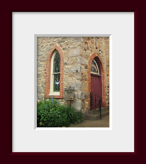 A gothic stone church with spring flowers blooming under the arched stained glass window