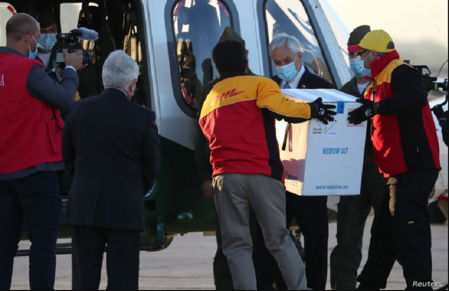 El presidente de Chile, Sebastián Piñera, observa mientras los trabajadores llevan el primer lote de la vacuna Pfizer-BioNTech COVID-19 a un helicóptero. Chile, jueves 24 de diciembre de 2020 / REUTERS