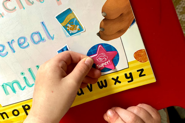super sticker Close up of a child sticking on a star shaped super sticker to the adventures of paddington magazine