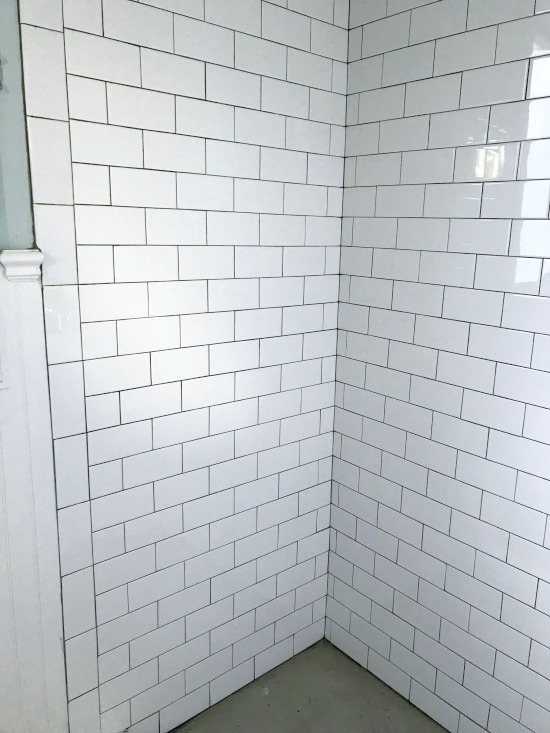 white subway tile shower with dark grout