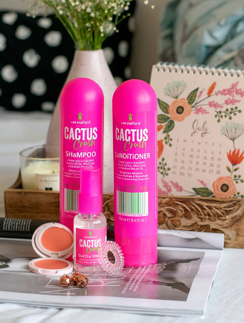 Lee Stafford Cactus Crush shampoo and conditioner, pink bottles. Cactus Crush dazzle drops, invisibobble and peach cream blusher on magazine with July calendar on tray in background with flowers in blush pink vase