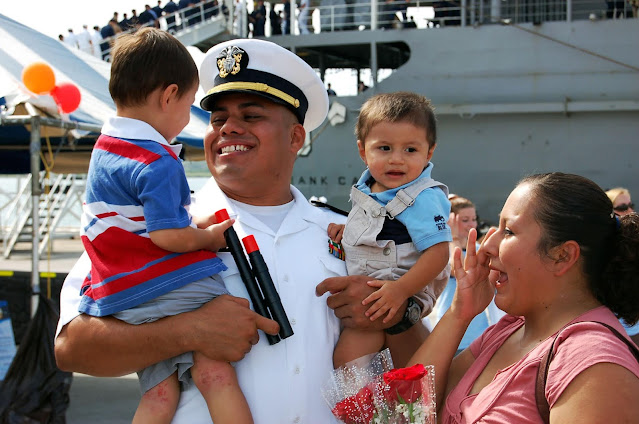 A photo of a military man holding his two young children