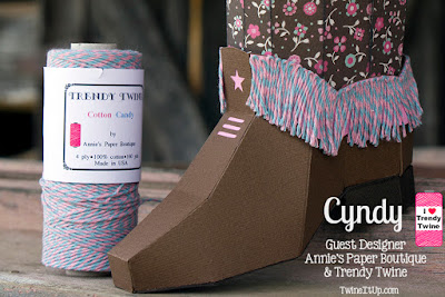 3d paper cowboy boot with a pink and blue twine fringe around the bottom half of boot