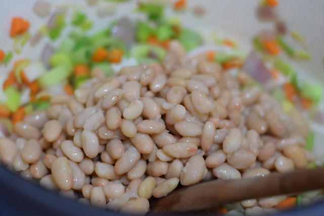 The white beans being added to the pot.