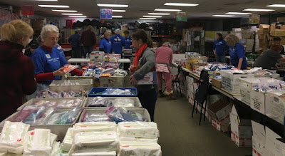 The volunteers are getting instructions on the best way to pack a box to maximize the postage dollars.