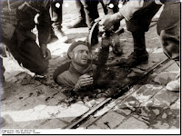 Germans pull out  Armia Krajowa man from  man hole Warsaw Uprising 1944