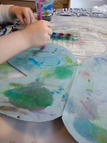 Toddler painting the wings of her dress up butterfly wings