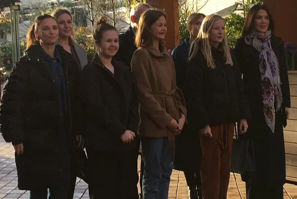 Crown Princess Mary wore a trench coat by Fonnesbech, and high-heel boots by Pura Lopez, and gold earrings by Marianne Dulong. Prada Saffiano bag