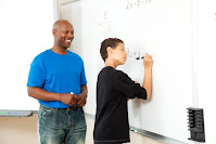 Teacher watching student write on white board