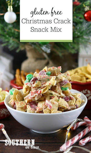 Easy Gluten Free Christmas Crack Snack Mix Recipe - Snack mix with Chex cereal, Christmas M&M's, Christmas sprinkles and crushed candy canes in front of Christmas tree with candy canes and fairy lights in foreground