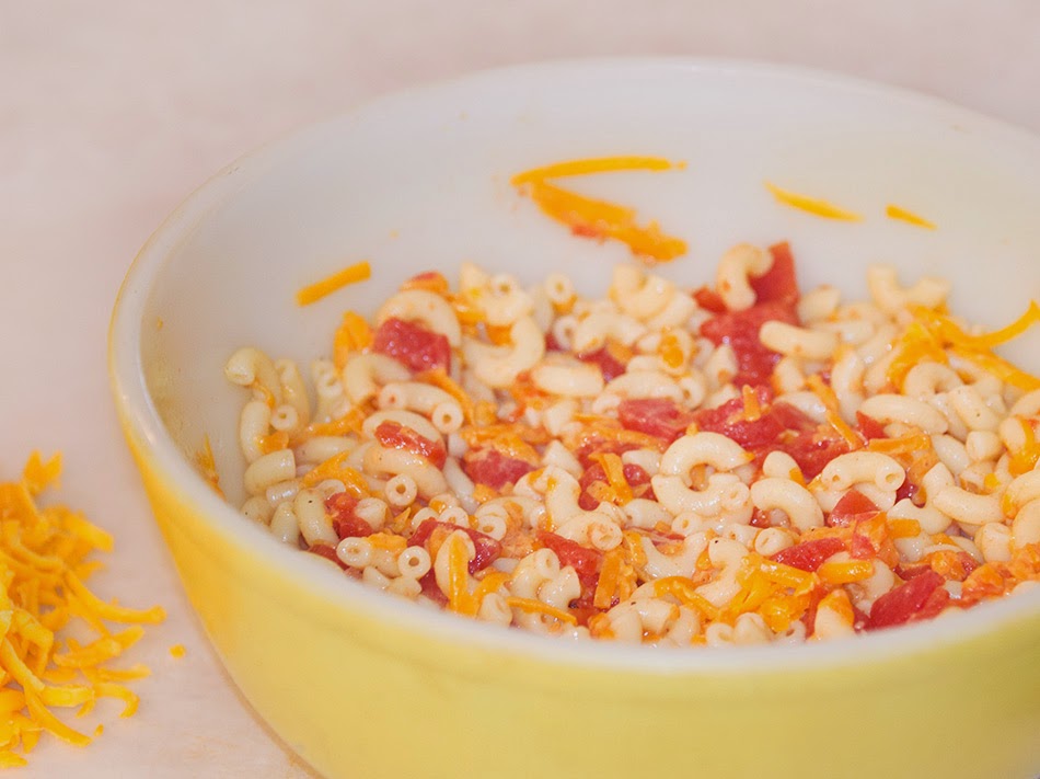 Old yellow pyrex bowl with tomato, elbow macaroni, cheese - ready to be put in the oven and bake.