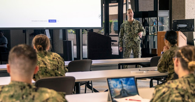 A man speaks in front of a group of uniformed people.