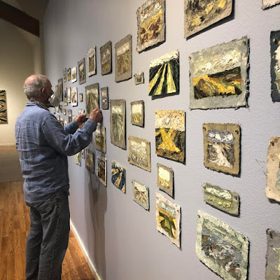 Artist John Robertson standing with 65 paintings that have been installed at the Wildling Museum in Solvaang, Ca for an art echibition