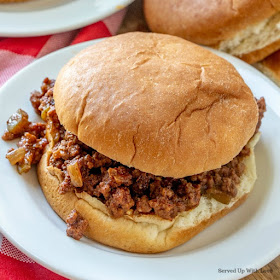Ground meat in sauce on a hamburger bun on white plate