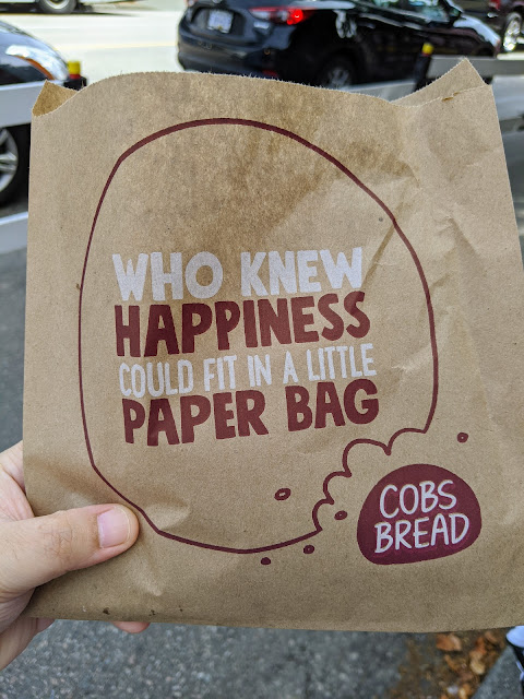 "Who knew happiness can fit in a paper bag" is printed on a paper bag with COBS Bread logo