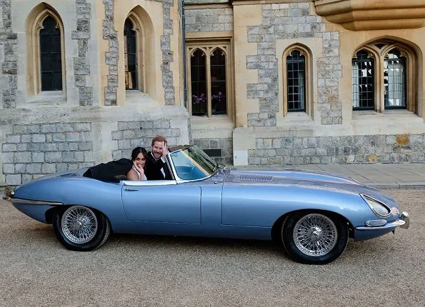 Prince Harry and Meghan Markle, Duchess of Sussex, in an E-Type Jaguar. Meghan wears a bespoke Stella McCartney high neck lily white gown