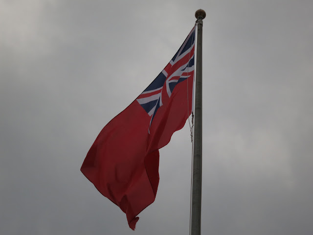 Red Ensign Flag flying against a grey sky.
