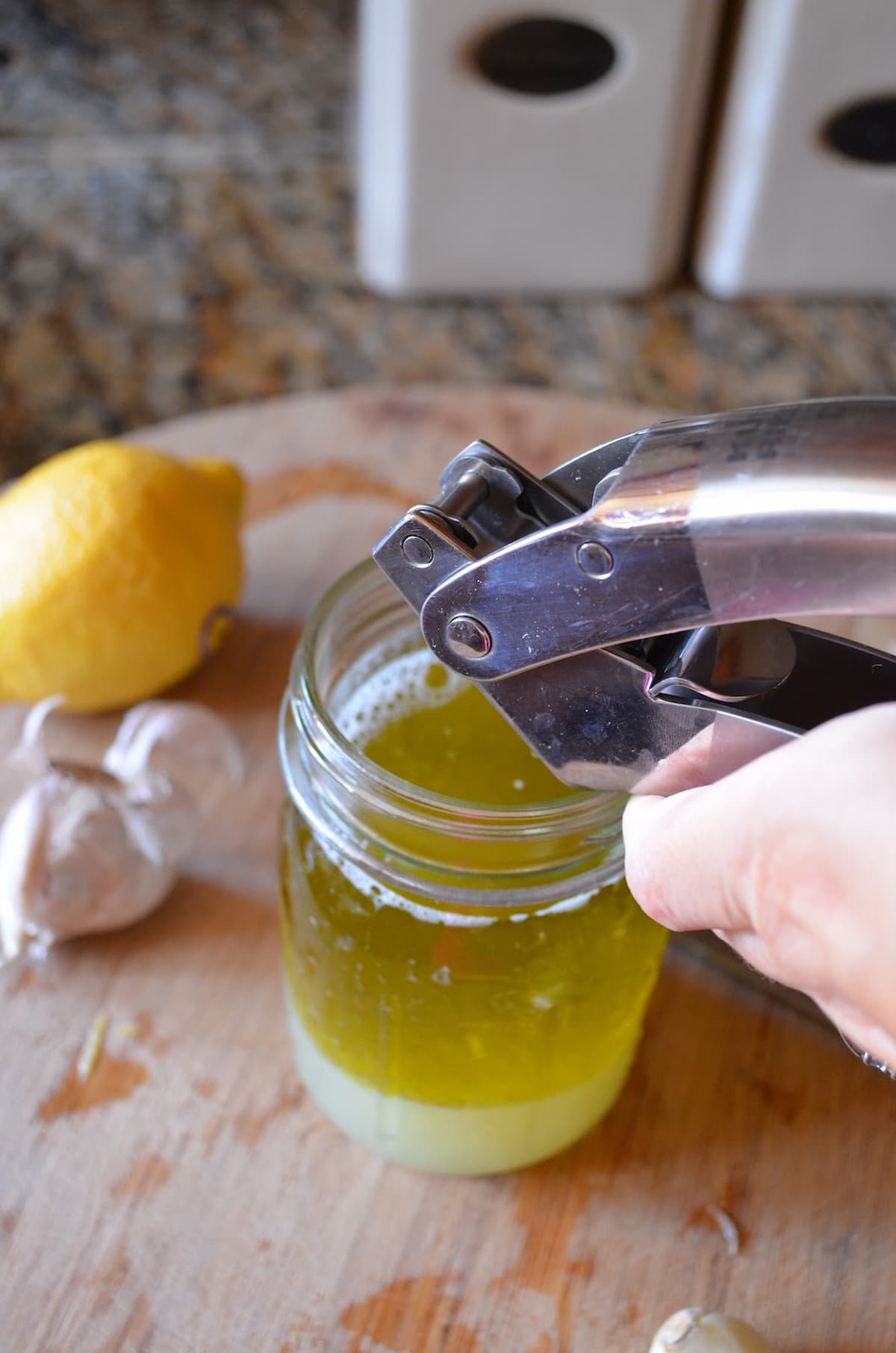 Garlic being pressed into Lemon Vinaigrette.