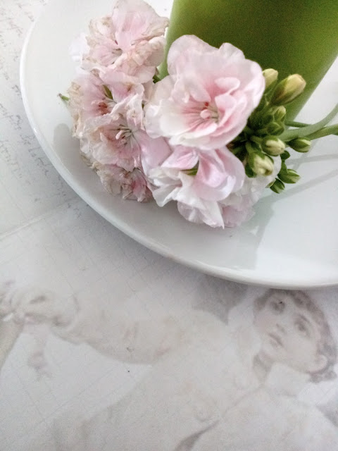 Centro de mesa con ramo de geranio, vela y un plato blanco