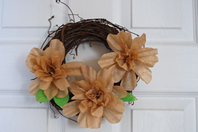 Small flower wreath on a door with spring green leaves added.