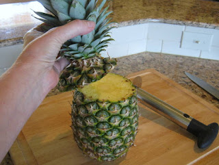 Using the sharp knife, lay the pineapple on the cutting board and cut a couple of inches off the top. 