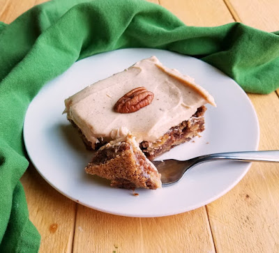 Moist and flavorful German apple cake is full of fresh apples and comes together quickly. The cinnamon brown sugar cream cheese frosting takes it to the next level! piece of dense german apple cake with cinnamon cream cheese frosting ready to eat