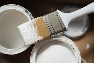 Foto imagem de duas latas de tinta com a tampa aberta na cor branca e um pincel de cerdas sujo de tinta branca representando textos sobre benfeitorias em imóvel locado.