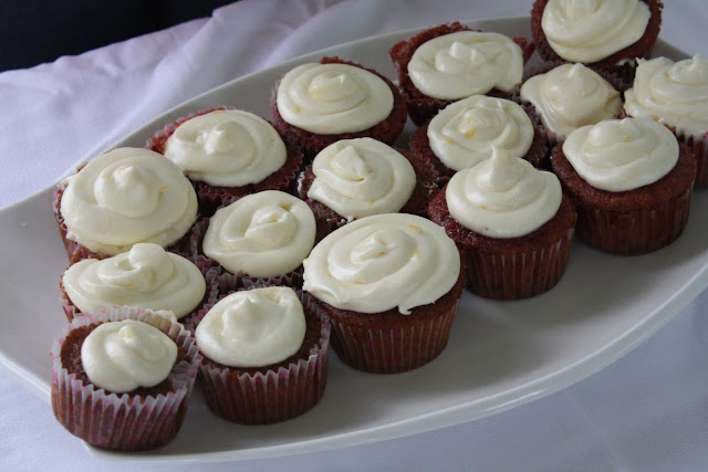 A batch of cupcakes with white icing on a white tray.