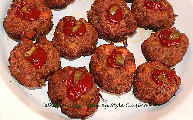these are miniature meatloaves made in a cupcake tin for individual servings. These are on a white plate with ketchup and baked green peppers on top