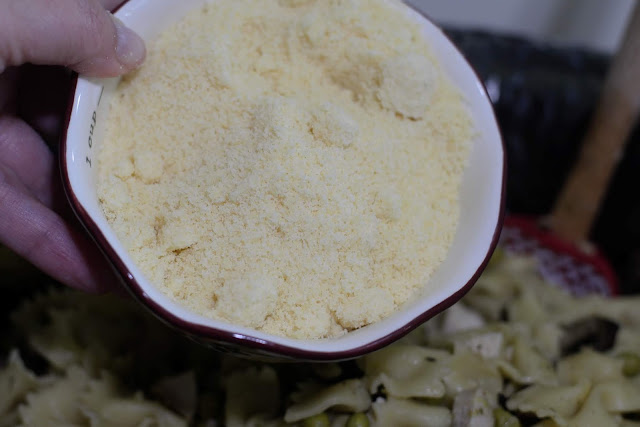 The grated parmesan cheese being added to the slow cooker. 
