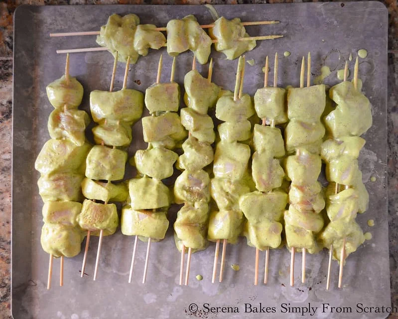 Green Curry Yogurt Marinaded Chicken placed on wooden skewers on cookie sheet.