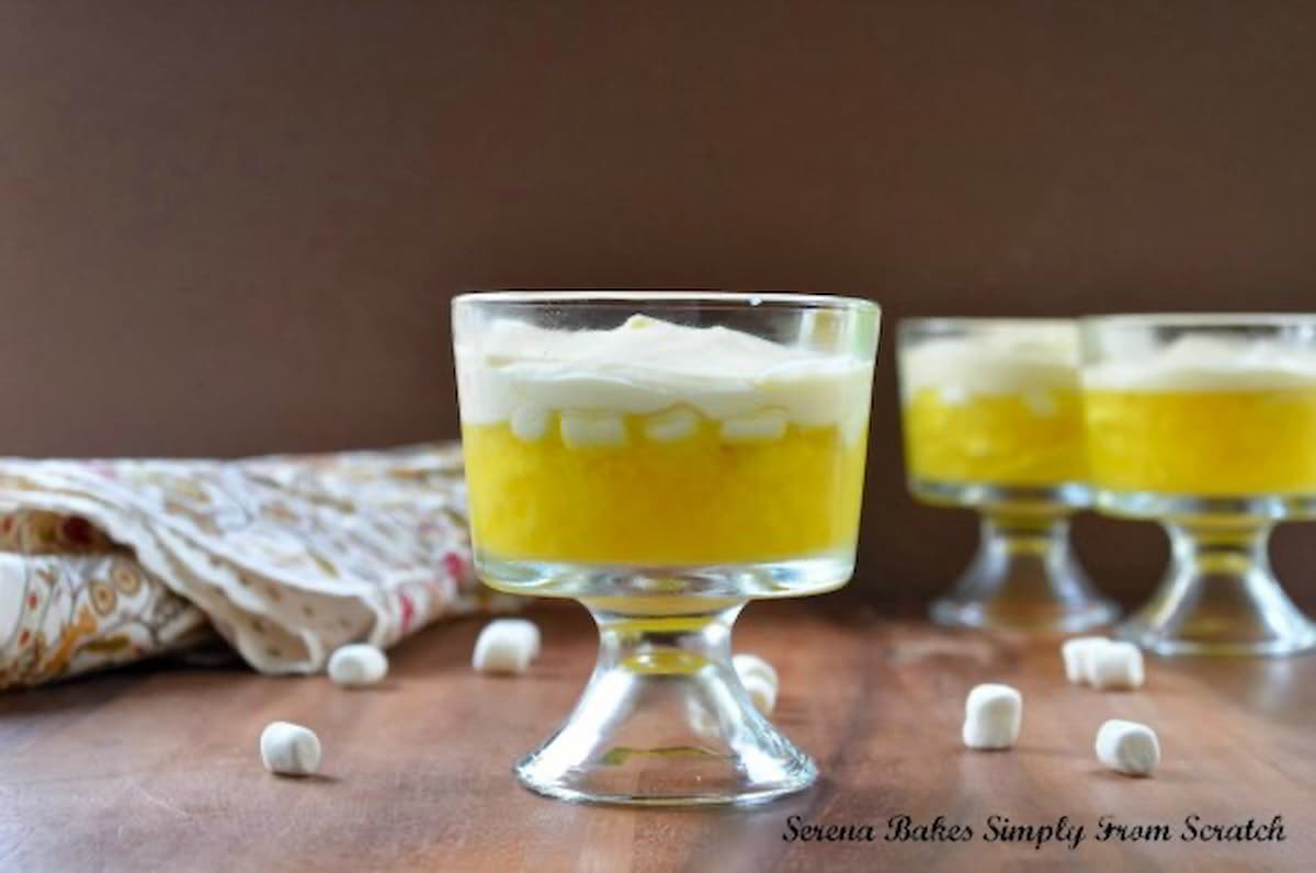 7 Up Jello Salad in parfait glasses. 7 Up Lemon Jello with crushed pineapple, banana and marshmallows. Then a layer of Pineapple Pudding Mousse.
