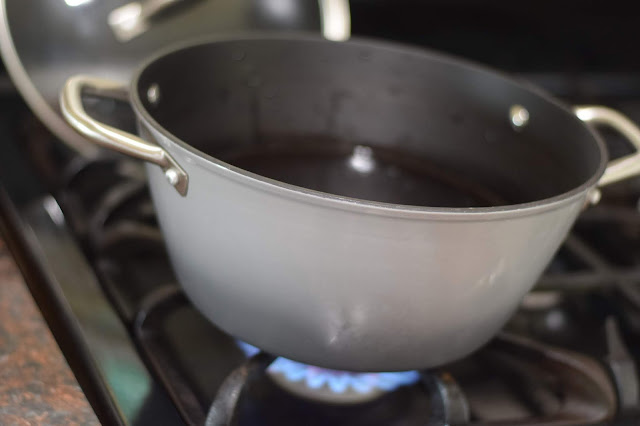 A large pot on the stove, full of water, coming to a boil. 