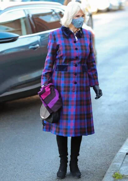 Duchess of Cornwall is wearing a face-mask and protective glasses. The Duchess wore a tartan coat dress, and a printed pattern scarf from Seasalt