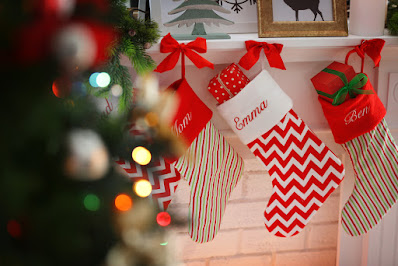 Monogrammed stockings hanging by a tree over the fireplace